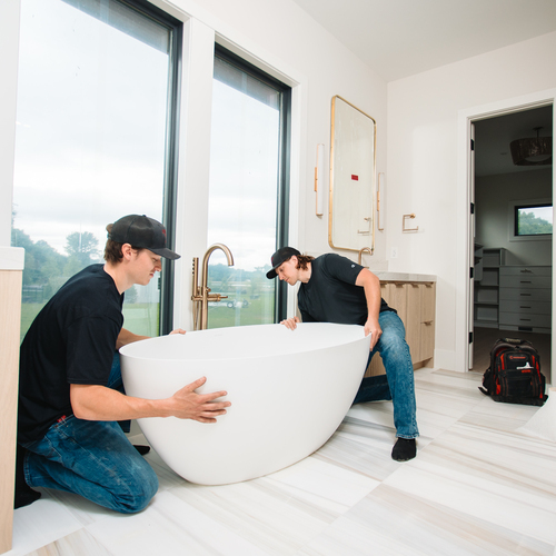 plumbers installing a bathtub